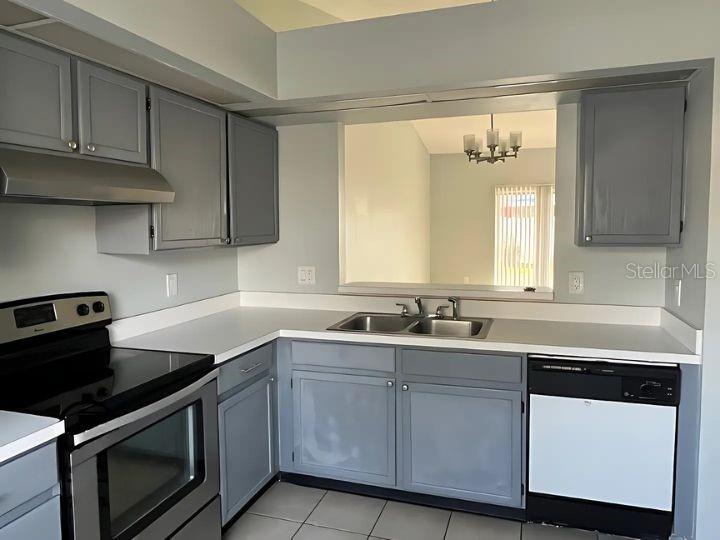 A kitchen features gray cabinets, white countertops, stainless steel appliances, and a pass-through window — 14796 LAGUNA BEACH CIRCLE, ORLANDO, FL