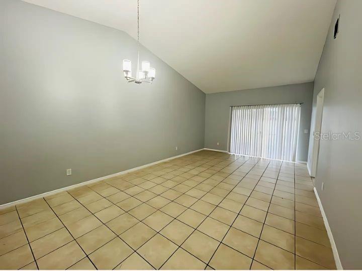 An empty dining room with light gray walls, a vaulted ceiling, and beige tile flooring — 14796 LAGUNA BEACH CIRCLE, ORLANDO, FL