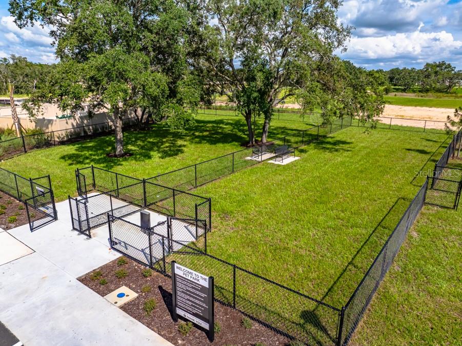 An aerial view of a fenced-in dog park with benches and mature trees — 13721 SQUALL LANE, HUDSON, FL