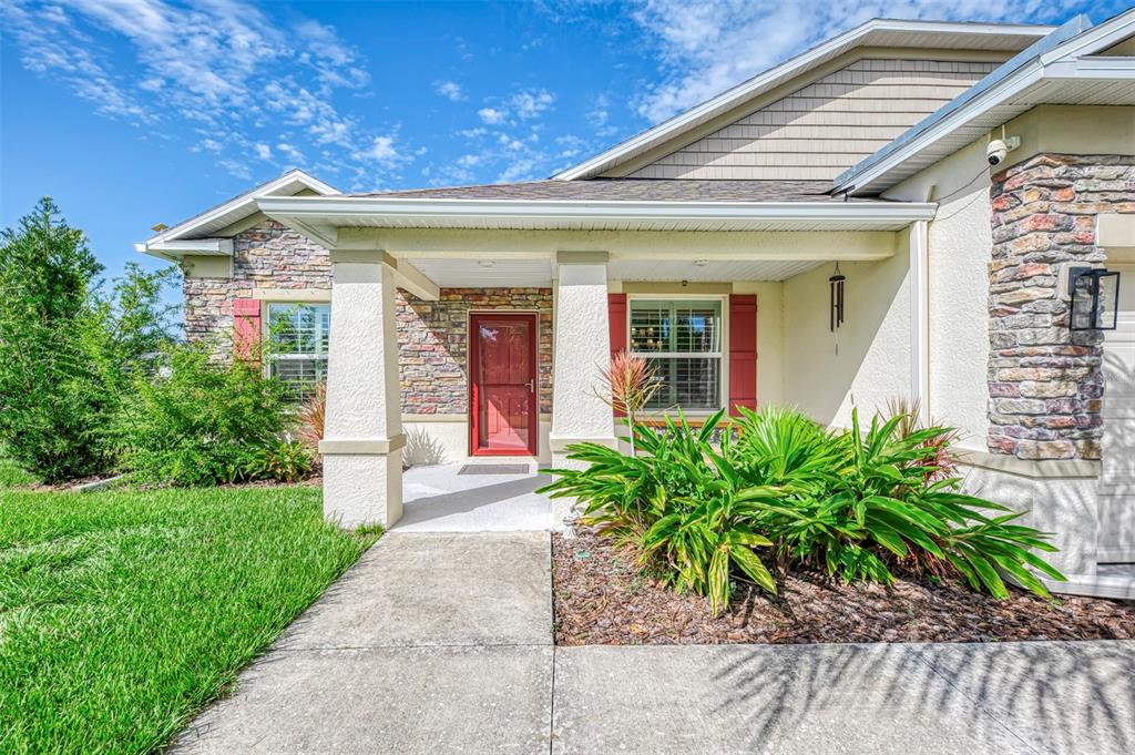 A single-story house exterior features a stone facade, a covered entryway, and a red door — 2705 LAMKIN ROAD, NORTH PORT, FL