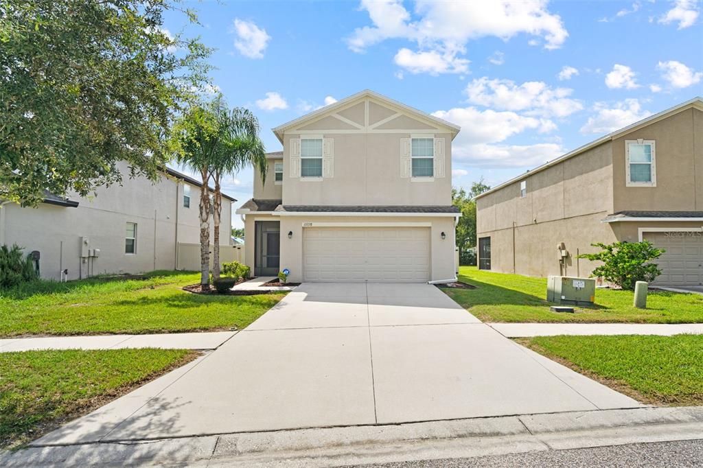 A two-story suburban house with a beige stucco exterior and a two-car garage — 13728 REINDEER CIRCLE, HUDSON, FL