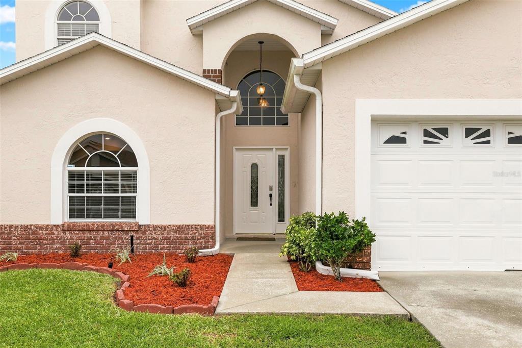 The exterior of a two-story house features a white front door, arched windows, and garage — 12827 DOWNSTREAM CIRCLE, ORLANDO, FL