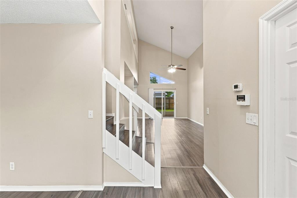 An interior view shows a staircase with white railings leading to a living area — 12827 DOWNSTREAM CIRCLE, ORLANDO, FL