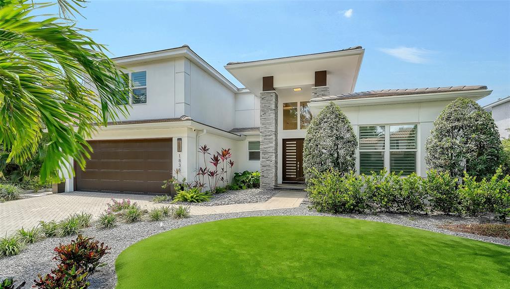 A two-story house features a brown garage, a stone-accented entryway, and a manicured lawn — 1838 OLEANDER STREET, SARASOTA, FL