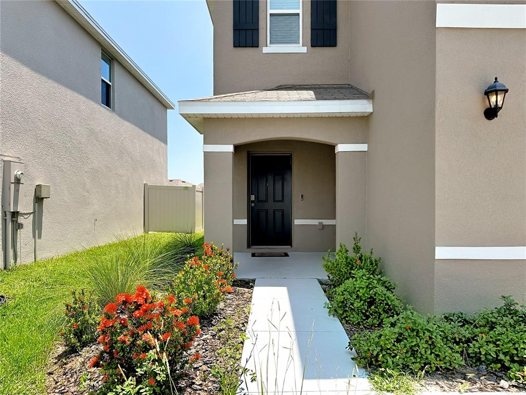 A concrete walkway leads to the front entrance of a two-story tan house — 12142 MOUNTAIN ISLAND TRAIL, PARRISH, FL