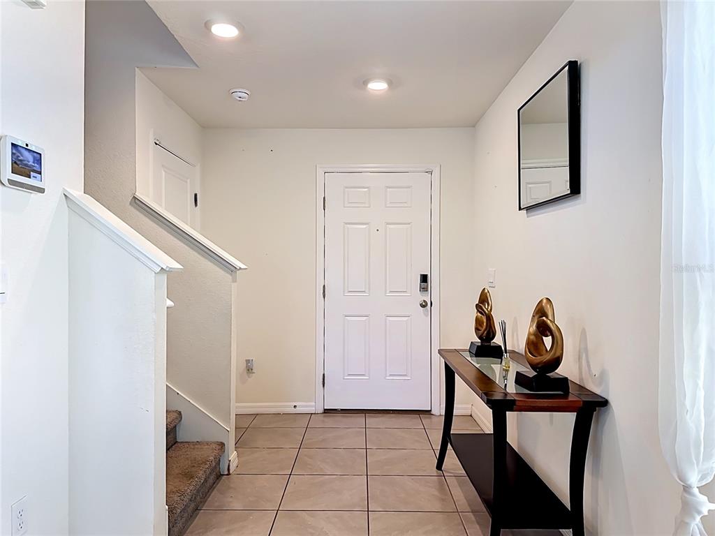 An entryway features tiled flooring, a staircase, a console table with decor, and a door — 12142 MOUNTAIN ISLAND TRAIL, PARRISH, FL