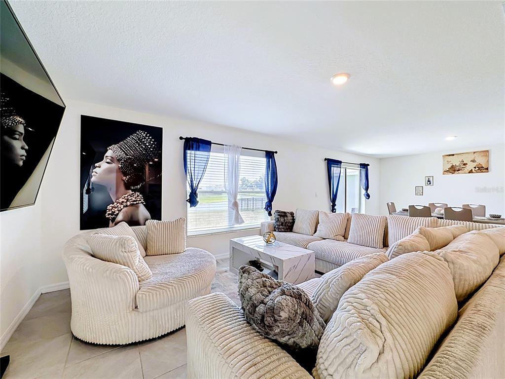 A living room features a large sectional sofa, a round chair, and wall art — 12142 MOUNTAIN ISLAND TRAIL, PARRISH, FL