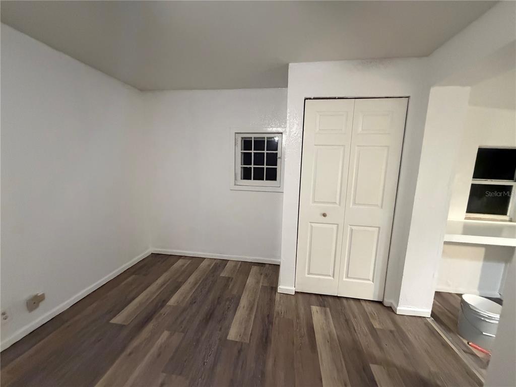 A room with white walls, wood-look flooring, a small window, and a white closet door — 410 W HOWRY AVENUE UNIT D, DELAND, FL