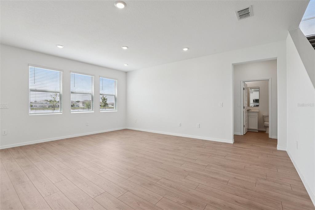 An empty room with light wood-look flooring, white walls, recessed lighting, and three windows — 5352 CLOUDBERRY AVENUE, LAKELAND, FL