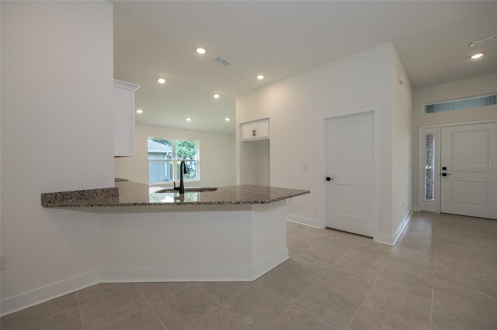An interior view shows a carpeted room opening into a living area with wood-look flooring — 7 ZIRCON COURT, PALM COAST, FL