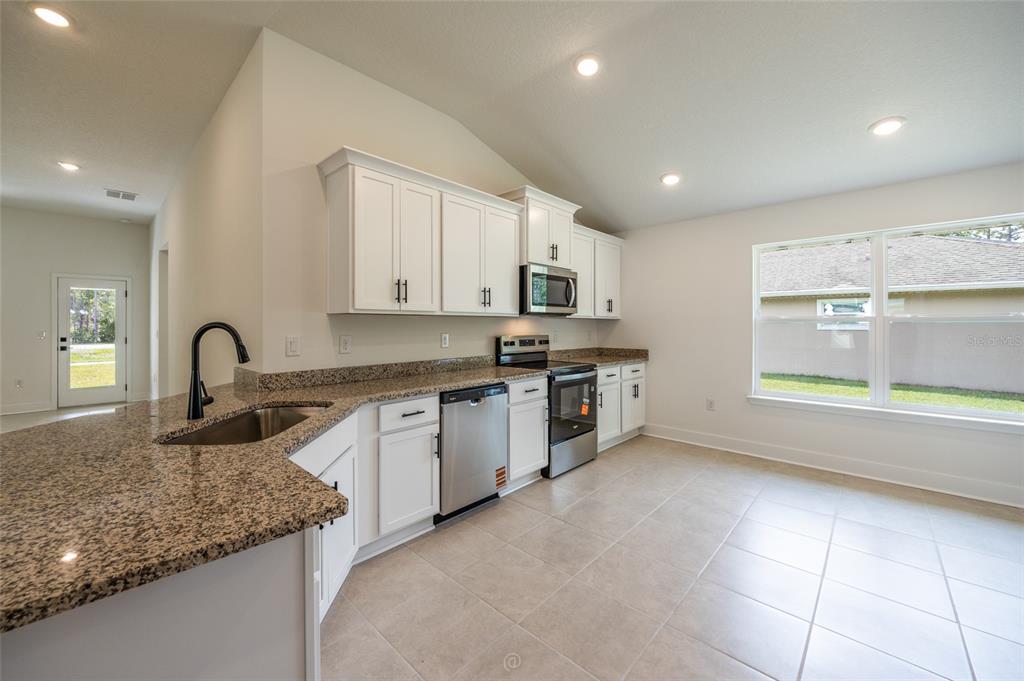 An open-concept kitchen and living area with white cabinets, light flooring, and recessed lighting — 7 ZIRCON COURT, PALM COAST, FL