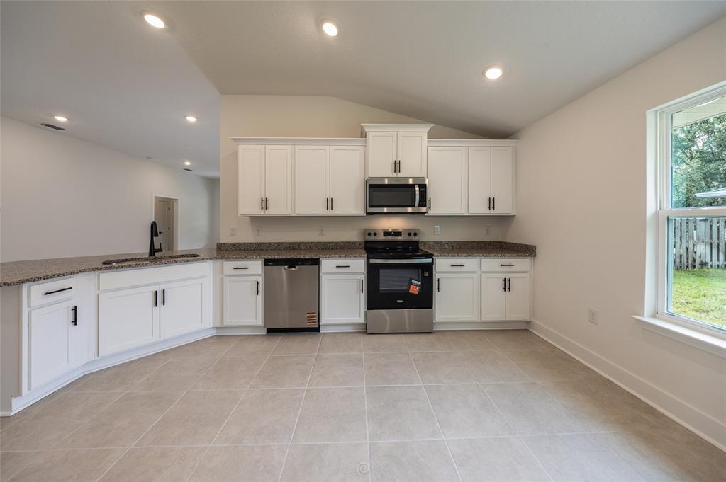 An empty living room with wood-look flooring, a ceiling fan, and a kitchen breakfast bar — 7 ZIRCON COURT, PALM COAST, FL