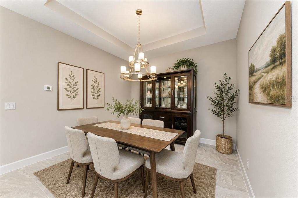 A dining room features a wooden table, six upholstered chairs, a hutch, and a chandelier — 6017 MESA GLEN, BRADENTON, FL