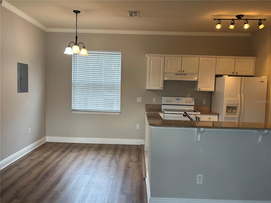 A kitchen with white cabinets, a white stove, and a dining area with wood-look flooring — 213 SOUTHERN PECAN CIRCLE UNIT 201, WINTER GARDEN, FL