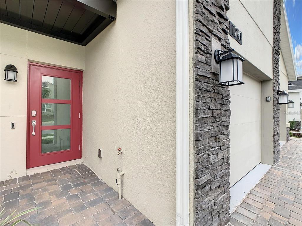 A red front door and a stone-accented garage entrance are visible on this home exterior — 1041 SPLASH SHOT PLACE UNIT 1041, DAVENPORT, FL