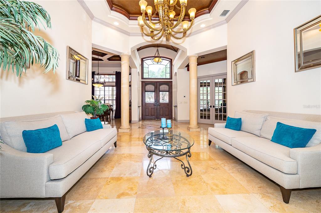 A formal living room features two beige sofas, a glass coffee table, and stone flooring — 2313 ROAT DRIVE, ORLANDO, FL