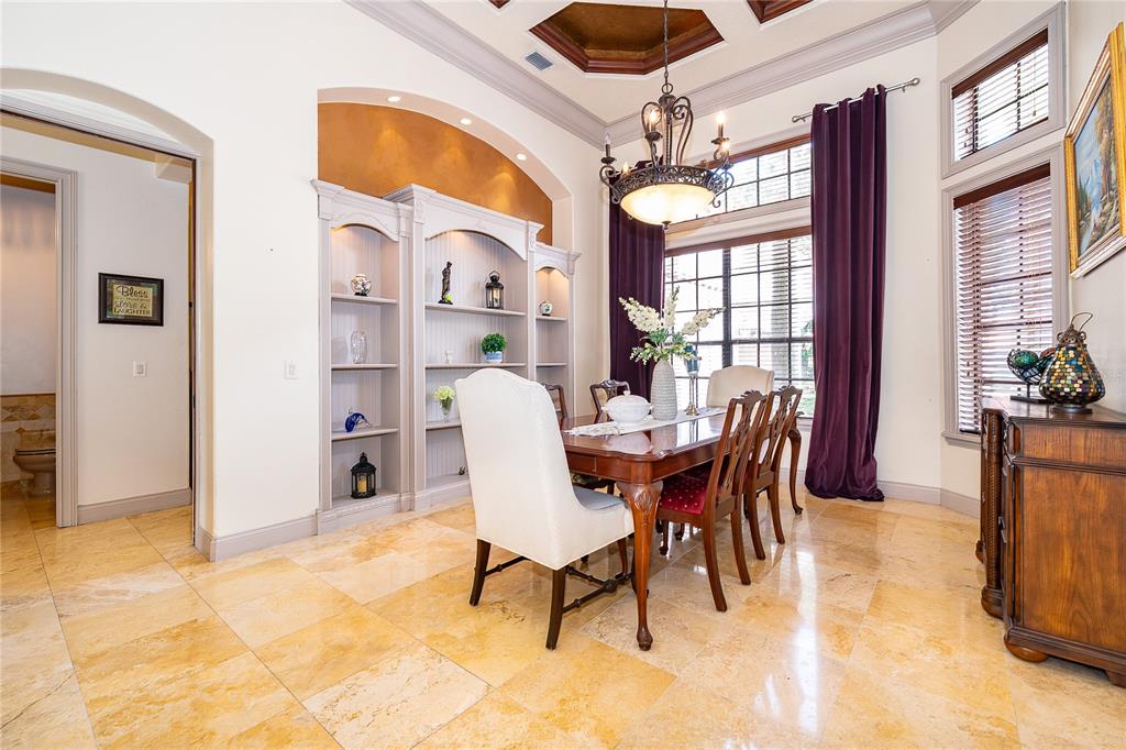 A formal dining room features a wooden table, upholstered chairs, built-in shelving, and tile flooring — 2313 ROAT DRIVE, ORLANDO, FL