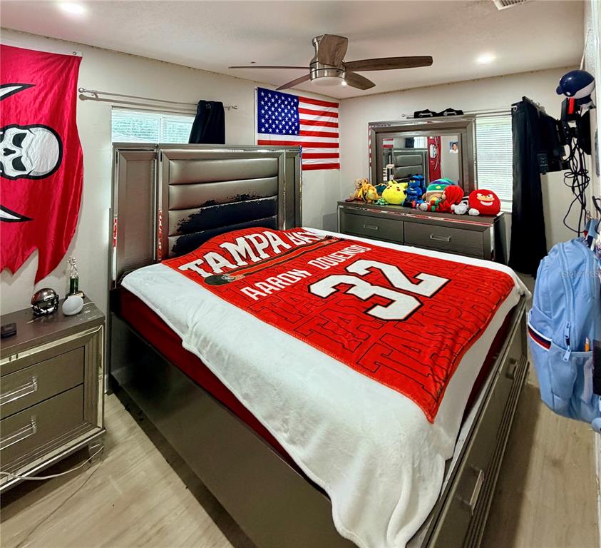 A bedroom features a bed with a Tampa Bay Buccaneers blanket, a dresser, and decor — 3620 N 56TH STREET, TAMPA, FL