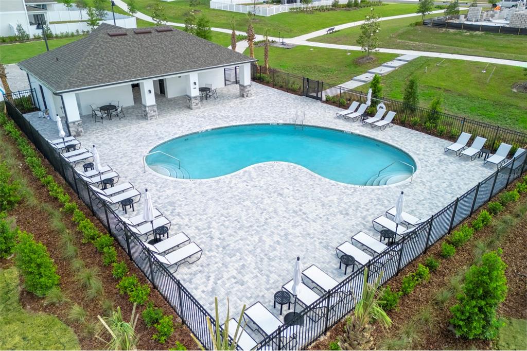 An aerial view shows a kidney-shaped swimming pool surrounded by lounge chairs and a pavilion — 4707 LAUREL SITE LOOP, APOPKA, FL