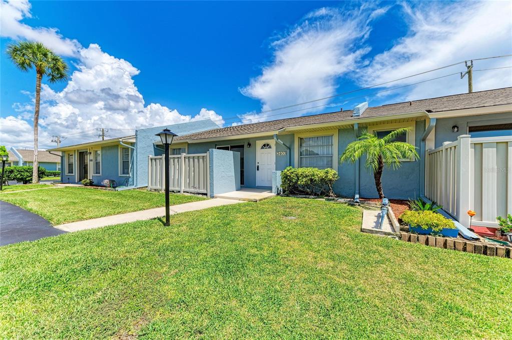 A single-story blue house with a white front door, a palm tree, and a lawn — 3403 36TH STREET W UNIT 109, BRADENTON, FL