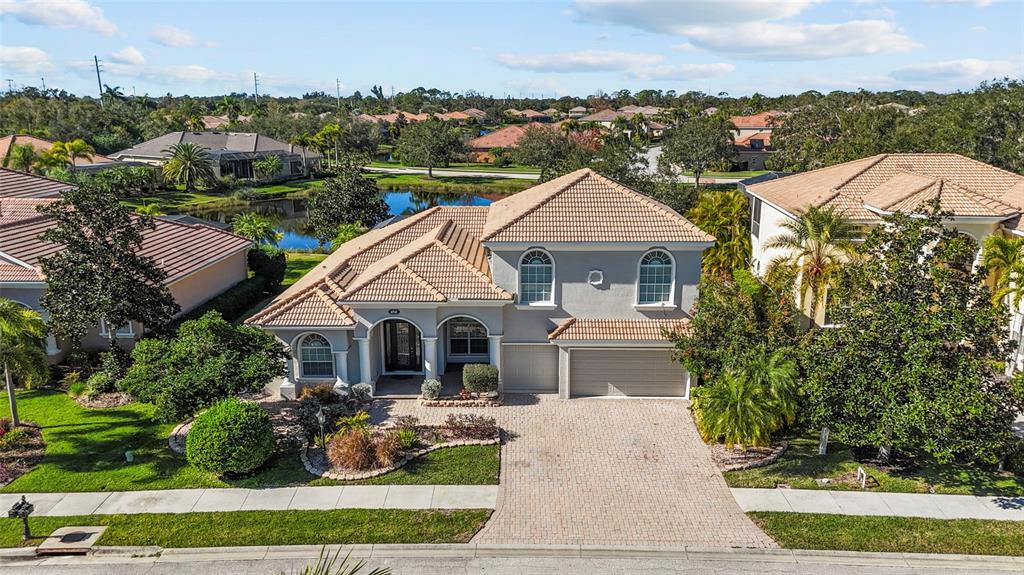 An aerial view of a two-story suburban house with a tiled roof and paver driveway — 6961 SCRUB JAY DRIVE, SARASOTA, FL