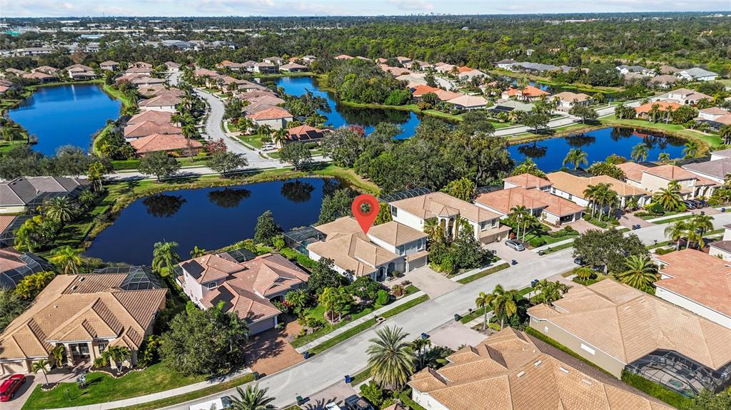 An aerial view shows a suburban neighborhood with houses surrounding several small lakes — 6961 SCRUB JAY DRIVE, SARASOTA, FL