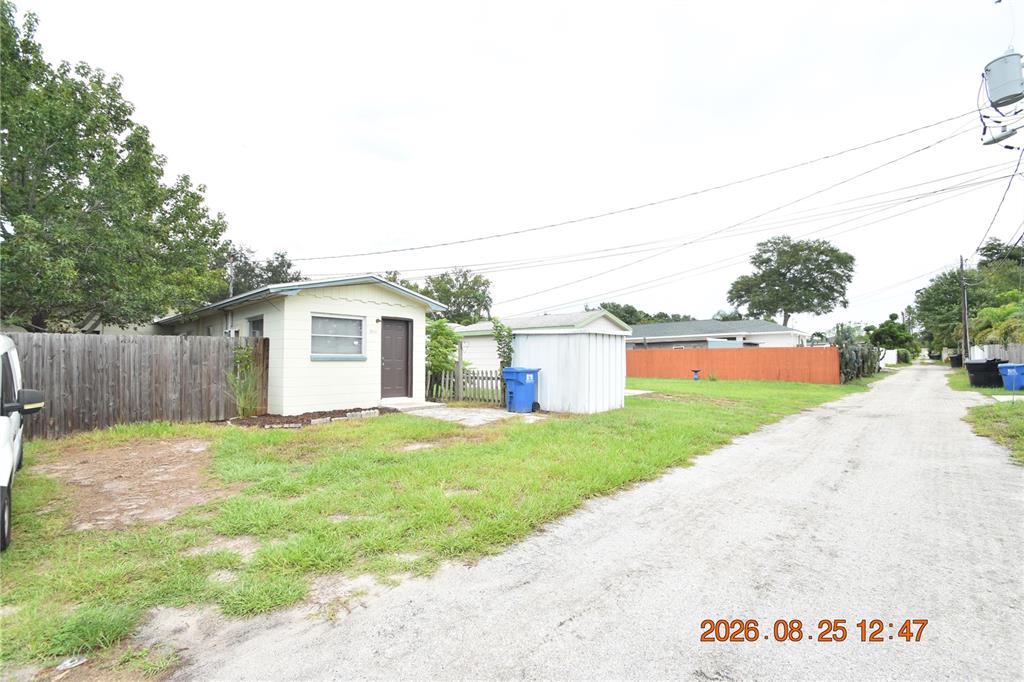 A small, light-colored house with a brown door sits beside a shed on a dirt road — 5124 18TH AVENUE N, ST PETERSBURG, FL