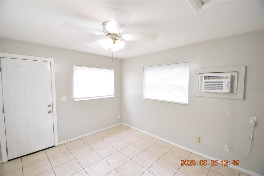A room with light-colored tile flooring, two windows, a ceiling fan, and a wall-mounted air conditioner — 5124 18TH AVENUE N, ST PETERSBURG, FL