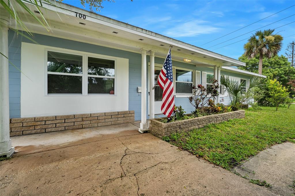 A single-story house with light blue siding, a brick planter, and an American flag — 700 KATHERINE STREET, SOUTH DAYTONA, FL