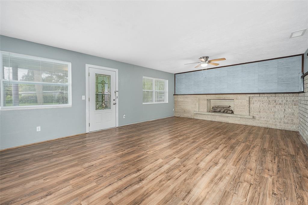 A living room features light blue walls, wood-look flooring, and a large stone fireplace — 700 KATHERINE STREET, SOUTH DAYTONA, FL