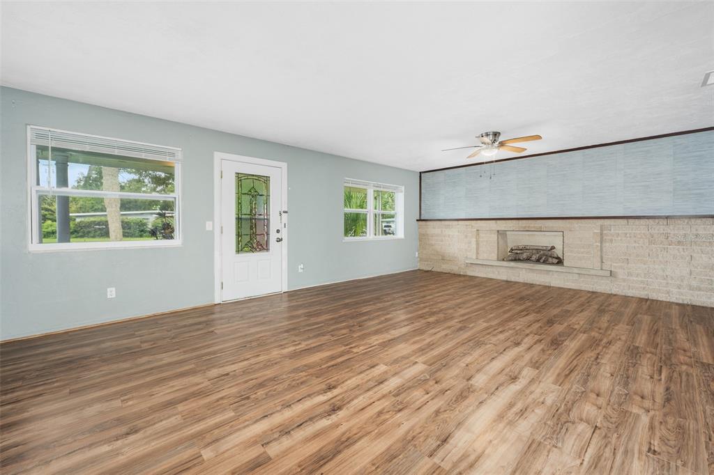 A living room features light blue walls, wood-look flooring, a front door, and a stone fireplace — 700 KATHERINE STREET, SOUTH DAYTONA, FL