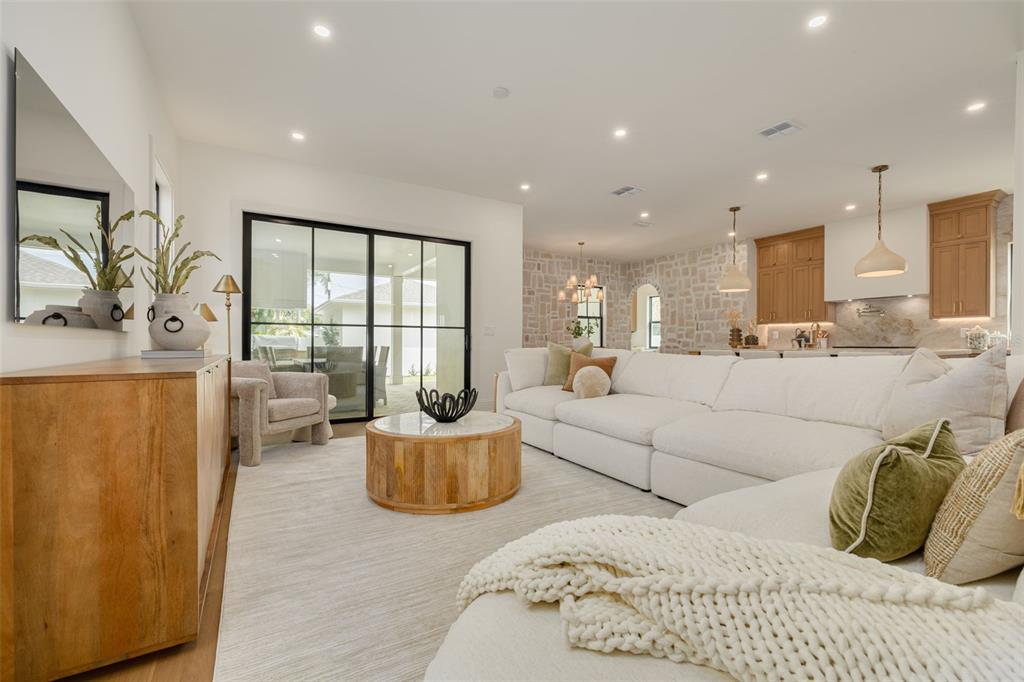 A bright living room features a large white sectional, wood coffee table, and sliding glass doors — 1037 26TH AVENUE N, ST PETERSBURG, FL