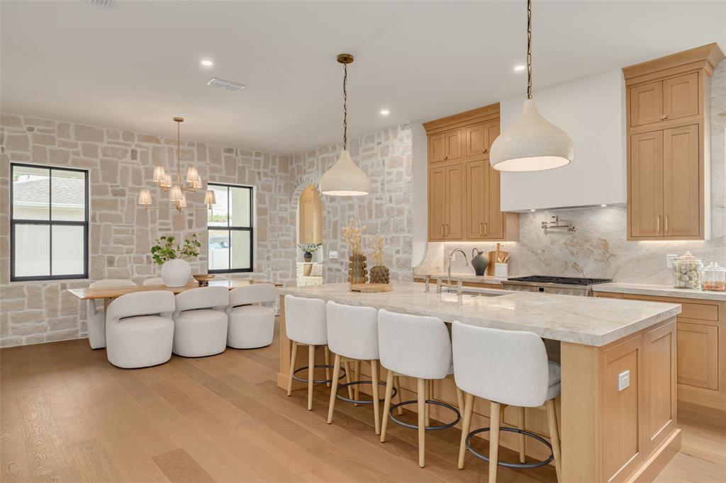 A kitchen and dining area featuring light wood cabinets, stone walls, and a large island — 1037 26TH AVENUE N, ST PETERSBURG, FL