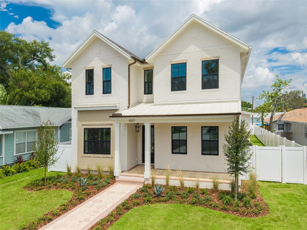 A two-story white brick house features a front porch, dark window frames, and landscaping — 1037 26TH AVENUE N, ST PETERSBURG, FL