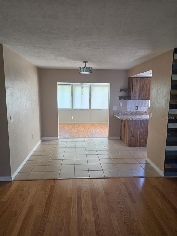 A dining area with tiled floors leads to a sunroom, adjacent to a wood-cabinet kitchen — 7315 SE 109TH PLACE, BELLEVIEW, FL