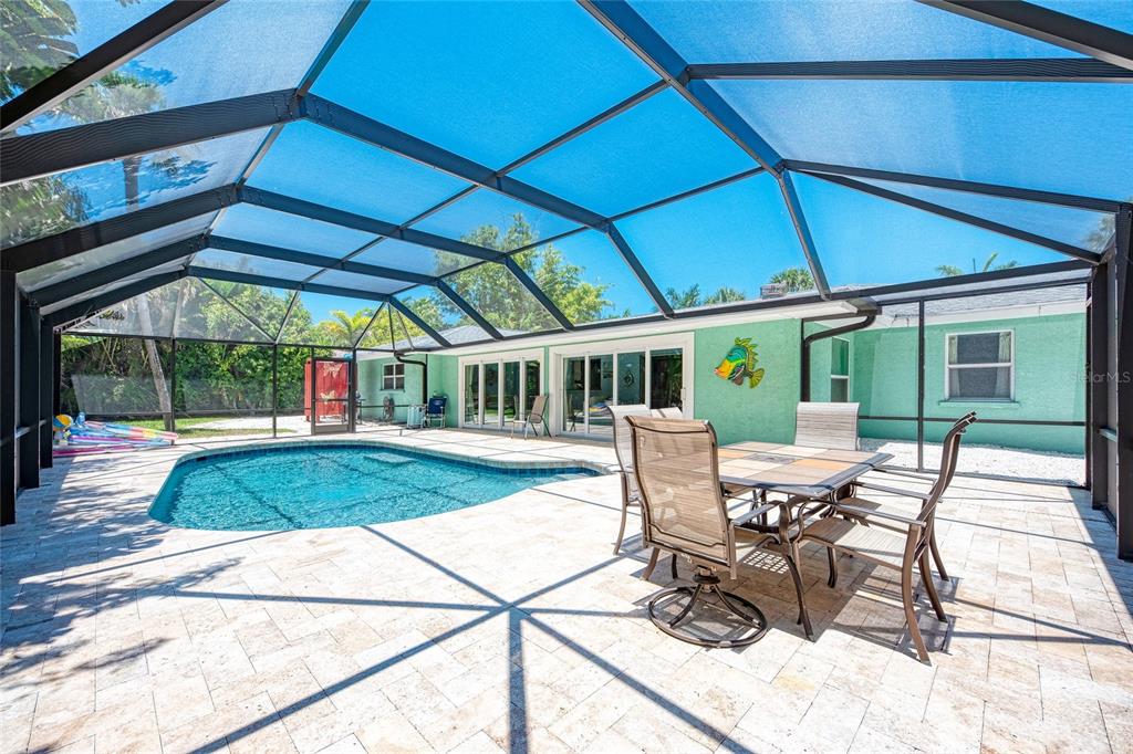 A screened-in patio features a swimming pool, outdoor dining furniture, and a light green house — 5640 CAPE LEYTE DRIVE, SARASOTA, FL