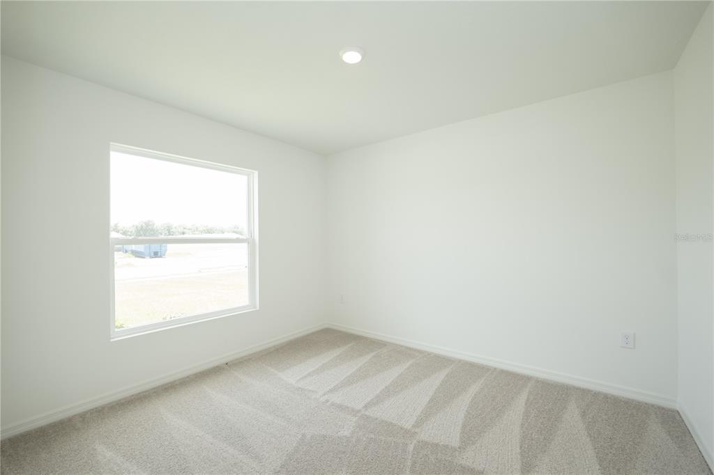 An empty bedroom features white walls, beige carpeting, a single window, and a recessed ceiling light — 3432 BLUEBERRY TRAIL, BARTOW, FL