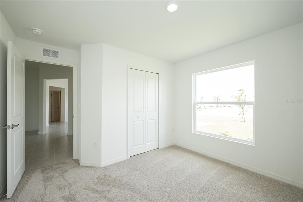 A bedroom with white walls, carpeted flooring, a closet, and a window overlooking a yard — 3432 BLUEBERRY TRAIL, BARTOW, FL