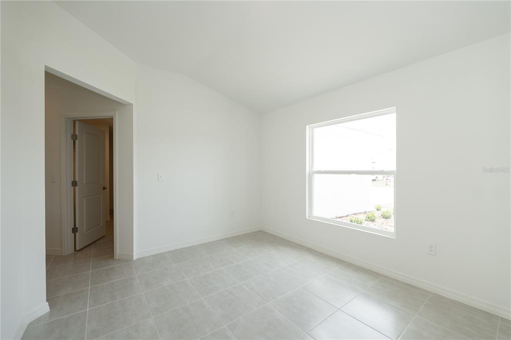 A bright, empty room features white walls, light-colored tile flooring, and a single window — 3432 BLUEBERRY TRAIL, BARTOW, FL