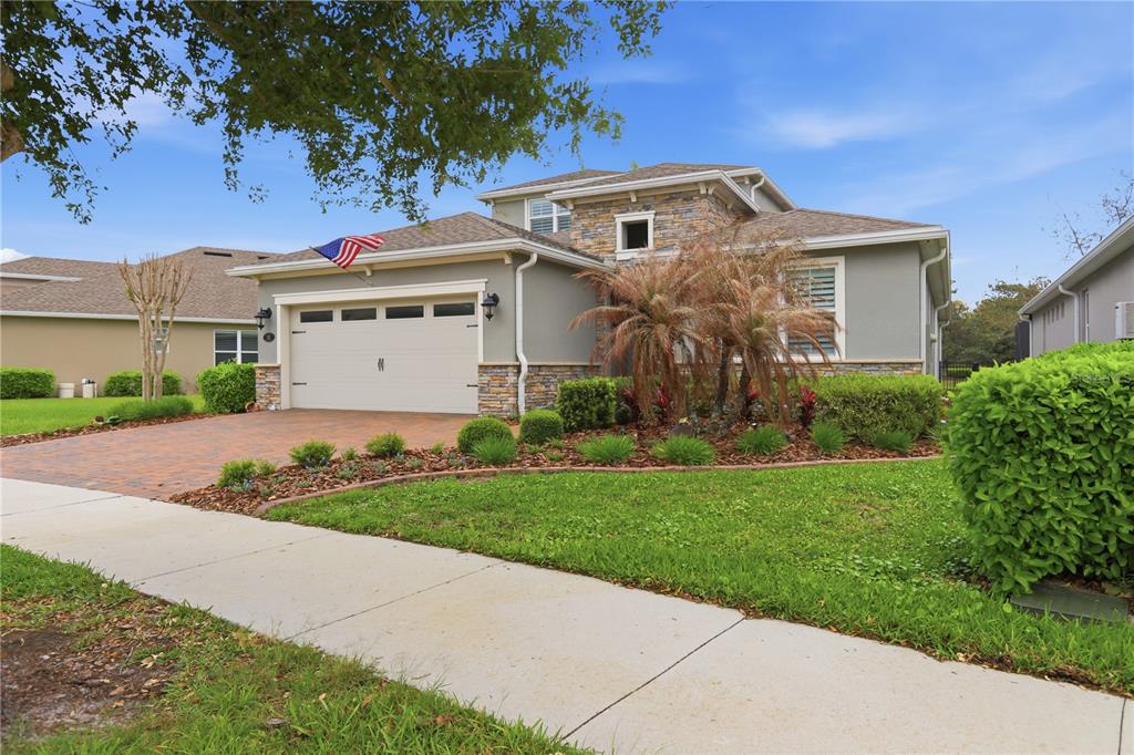 A single-story house with a stone facade, a two-car garage, and a brick paver driveway — 261 OLD MOSS CIRCLE, DELAND, FL