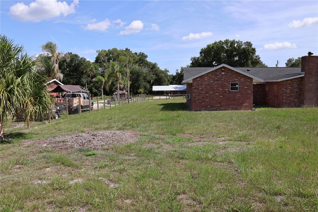 A brick house sits on a grassy lot with a fenced yard and parked truck — 699 BAKER STREET, WAUCHULA, FL