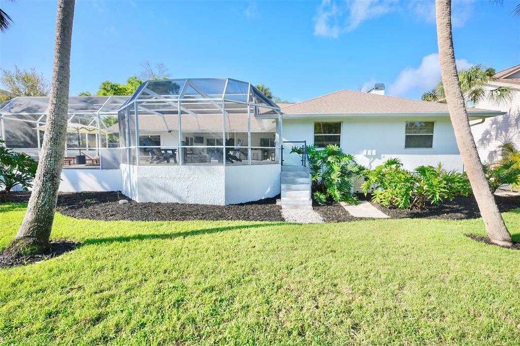 The exterior of a white house features a screened-in patio and a grassy lawn — 4717 E TRAILS DRIVE, SARASOTA, FL