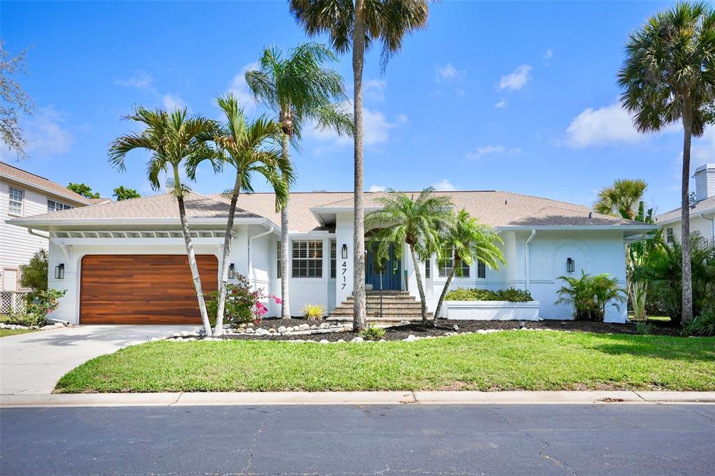 A single-story white house with a wooden garage door and palm trees in the front yard — 4717 E TRAILS DRIVE, SARASOTA, FL