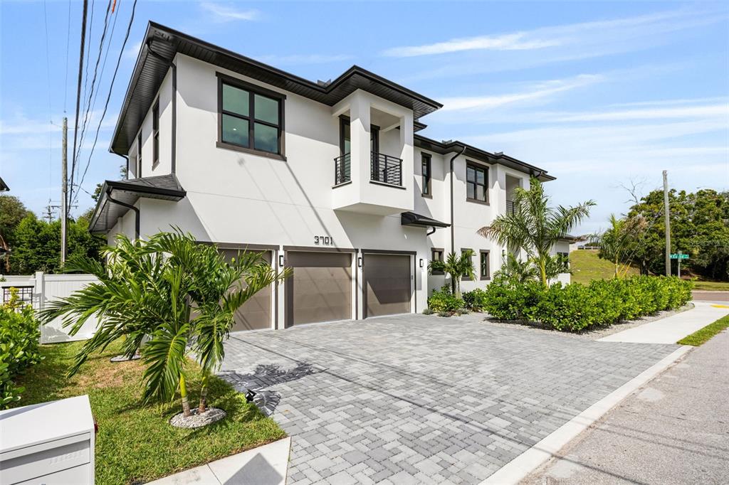 A modern white two-story house features a stone walkway, palm trees, and a dark entryway — 3701 S LYNWOOD AVENUE, TAMPA, FL