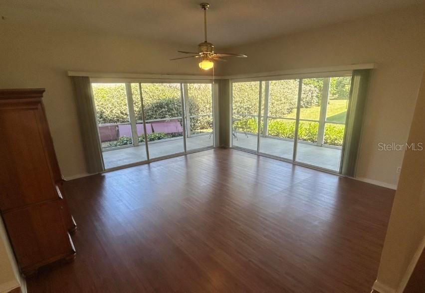 An empty room with wood-look flooring, a ceiling fan, and large sliding glass doors — 38 MAGNOLIA DRIVE S UNIT 38, ORMOND BEACH, FL