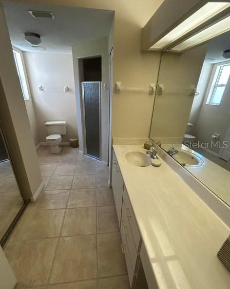 A bathroom features a long vanity with a mirror, tiled floors, and a separate toilet area — 38 MAGNOLIA DRIVE S UNIT 38, ORMOND BEACH, FL