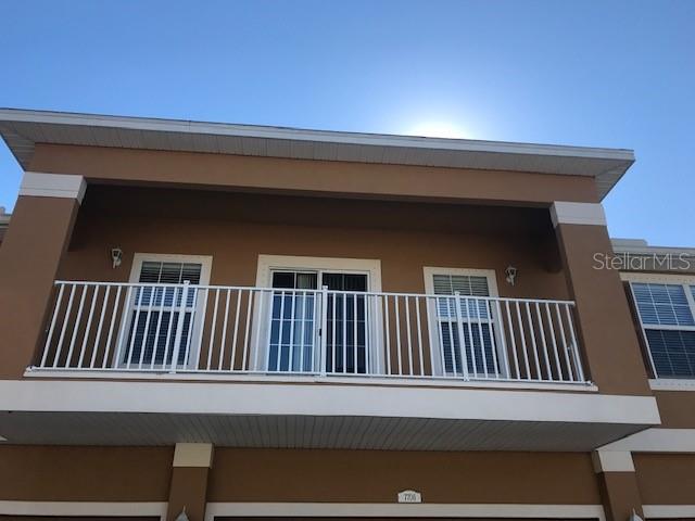 A brown building exterior features a second-story balcony with white railings and sliding glass doors — 7708 RED MILL CIRCLE, NEW PORT RICHEY, FL