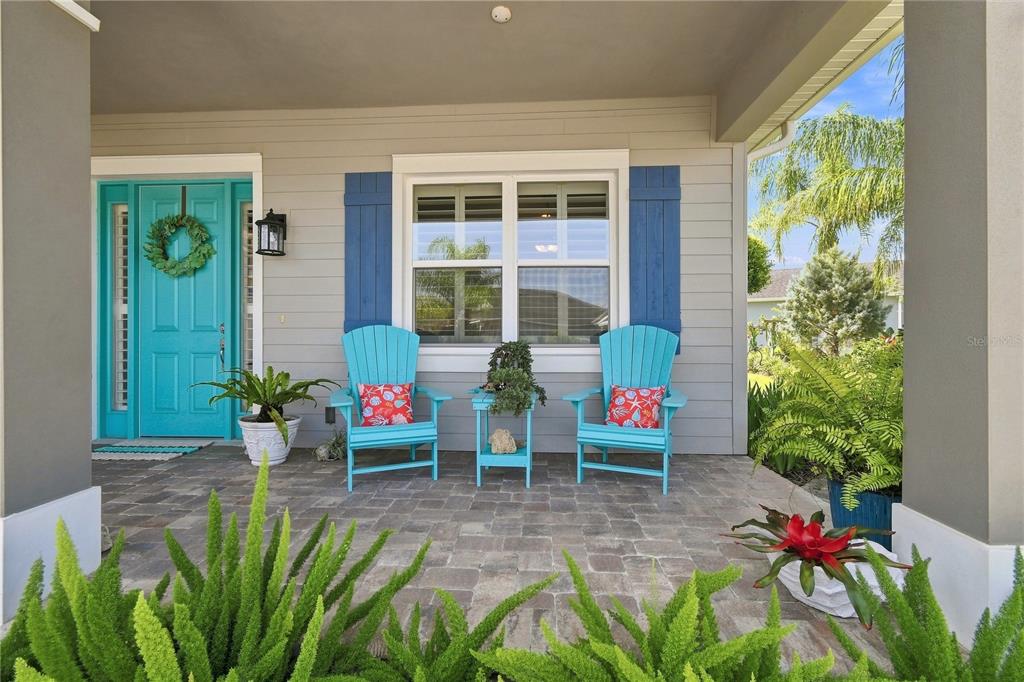 A covered front porch features two blue Adirondack chairs, a turquoise door, and potted plants — 2811 SIENNA VIEW TERRACE COURT, NEW SMYRNA BEACH, FL