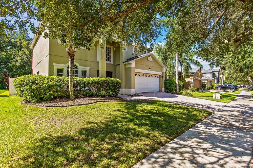 A two-story house with a beige stucco exterior, a two-car garage, and a front lawn — 11714 GREAT COMMISSION WAY, ORLANDO, FL