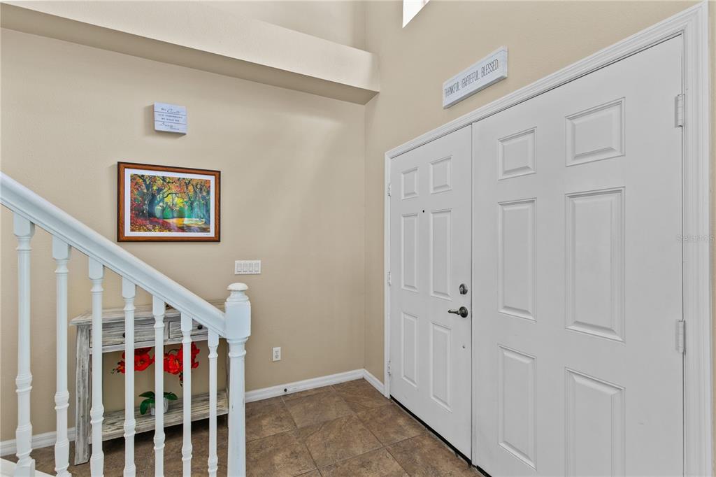 An entryway features a white double door, a staircase with white railings, and tile flooring — 11714 GREAT COMMISSION WAY, ORLANDO, FL